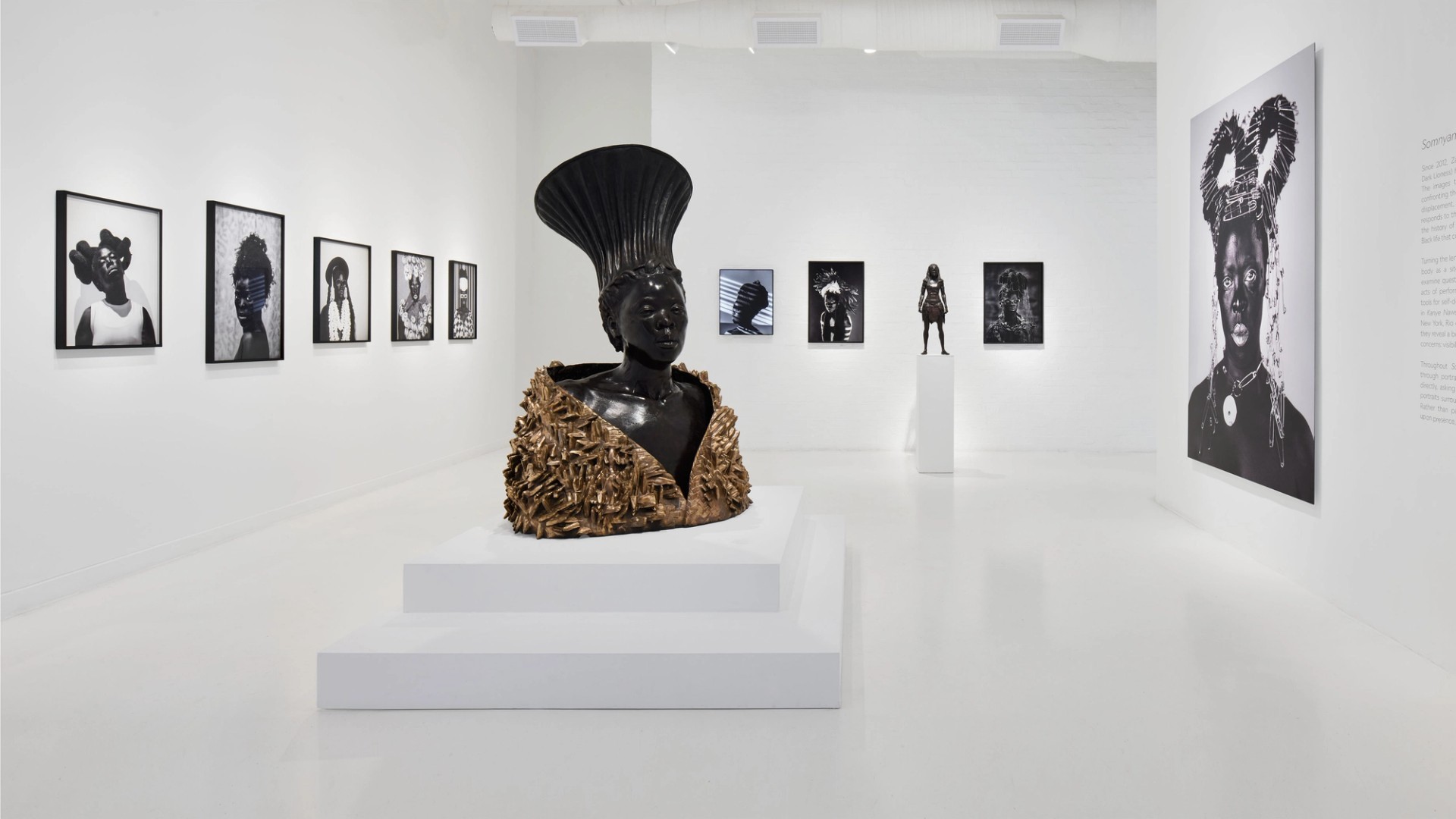 Installation view of Kanye Nawe at Southern Guild, framed portraits and a bronze sculpture on a white plinth