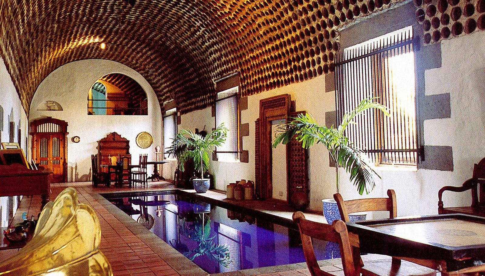 The interior of the Galerie du Moulin Cassé: terracotta pots lining a vaulted ceiling above a pool, tropical plants and terracotta floors